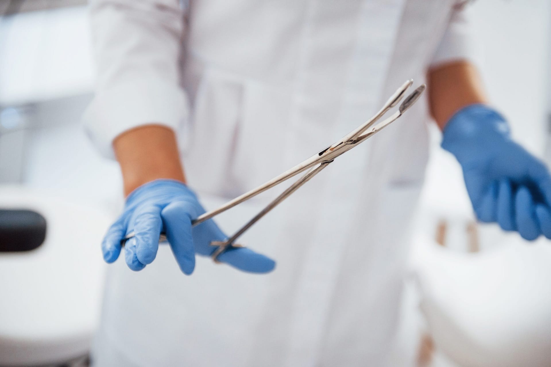 Close up view of female doctor hands that holds forceps doctor holding abortion tool